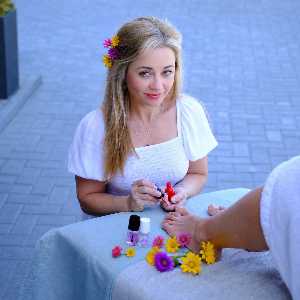 Little Daydream therapist applying red nail polish during a mobile manicure treatment